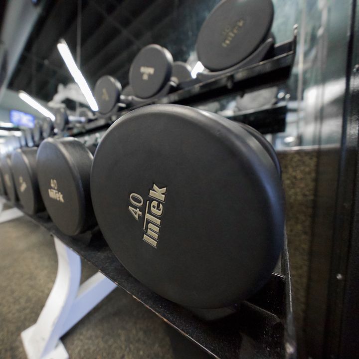 Close-up of a rack of round black dumbbells, the nearest stamped 40.